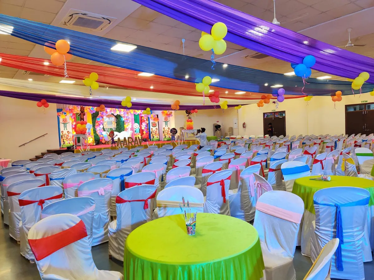 Colourful first birthday decor with balloons and a themed stage at Yeshwant Hall