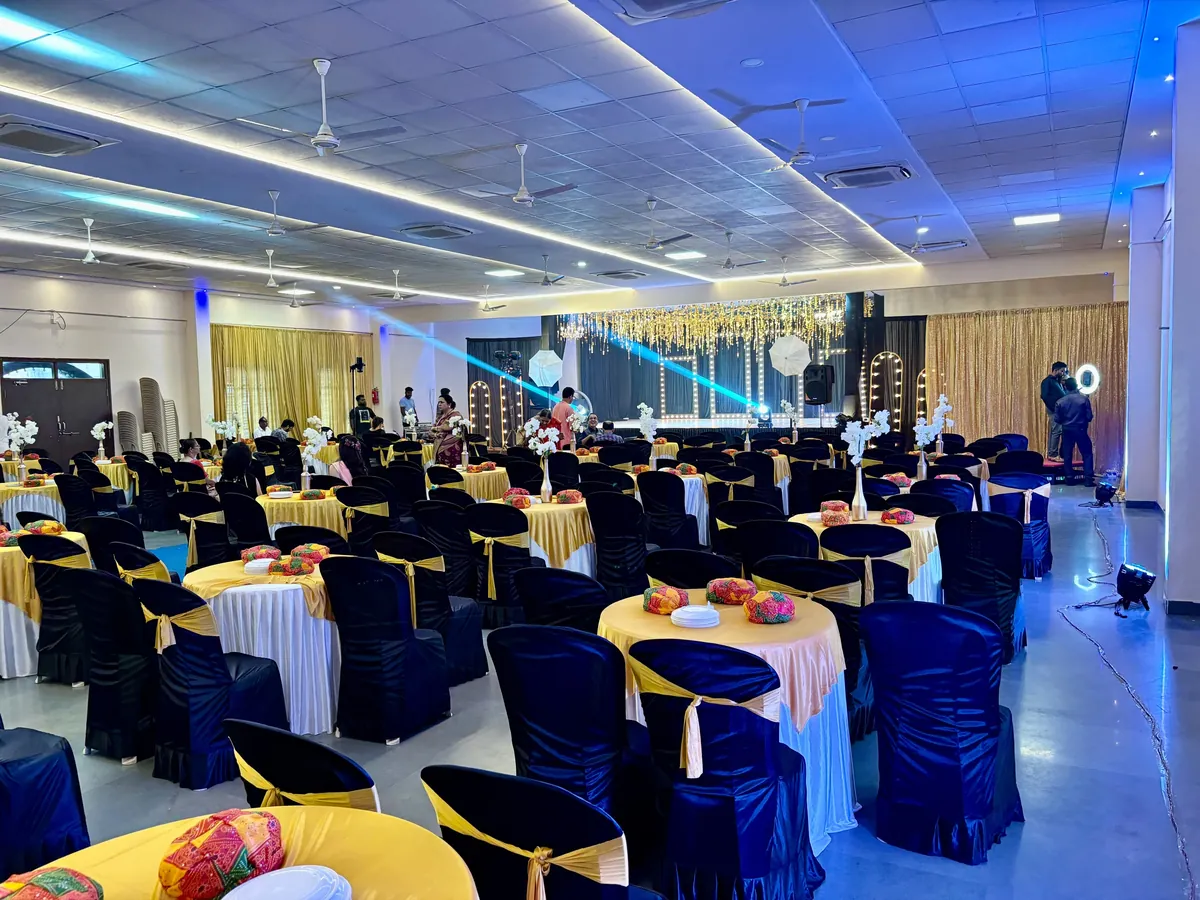 Floral wedding stage with guest seating in white and gold chair covers at Yeshwant Hall