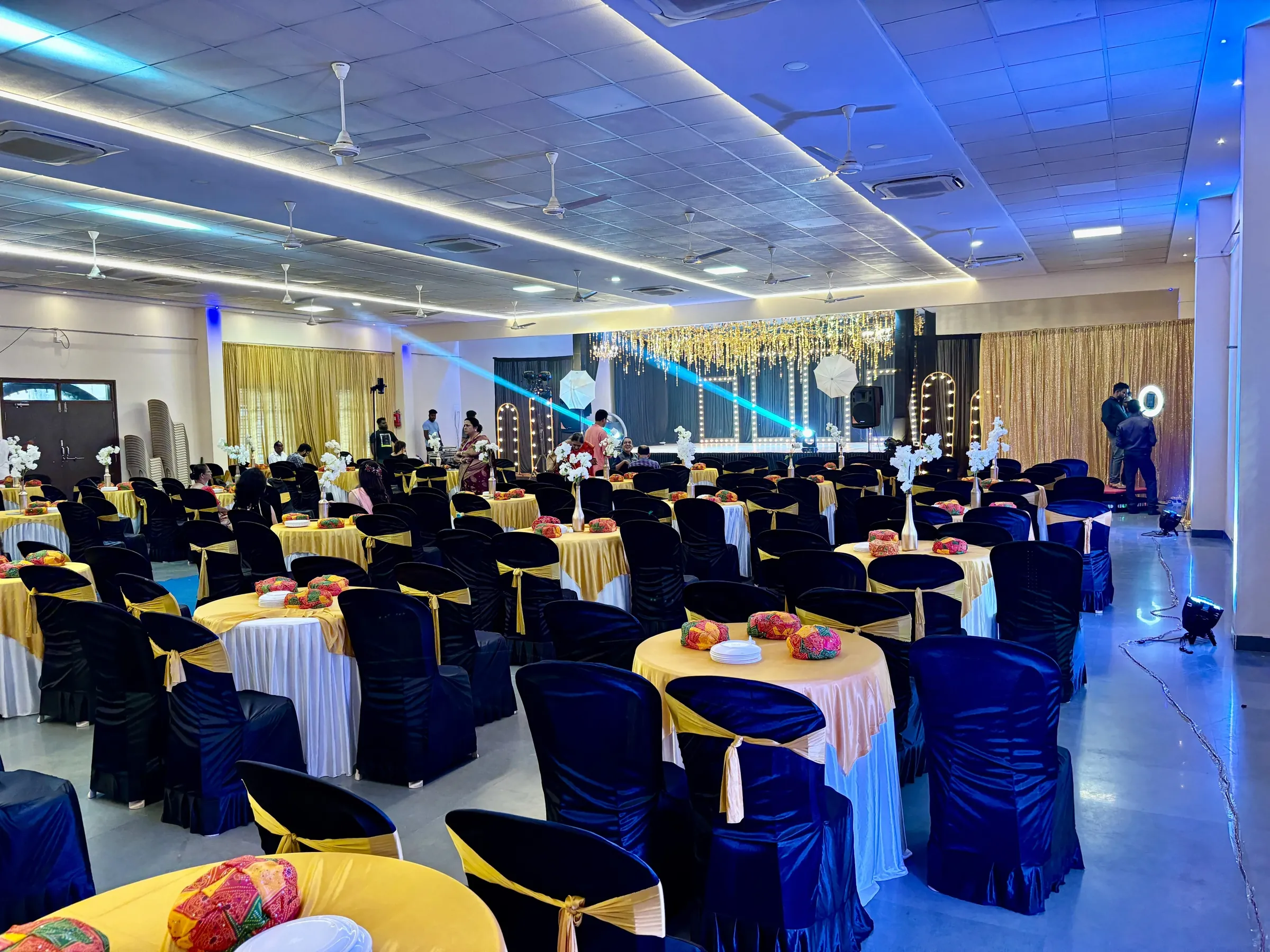 Floral wedding stage with guest seating in white and gold chair covers at Yeshwant Hall