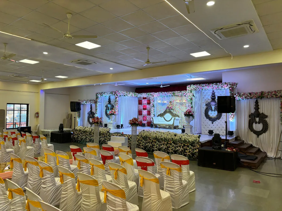 Evening celebration with a lit stage, gold drapes and round table seating at Yeshwant Hall